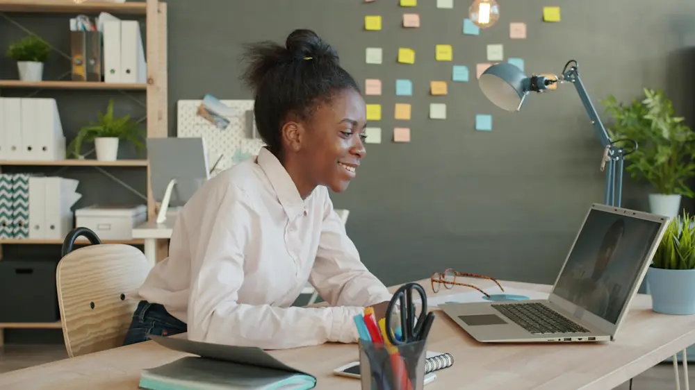A young woman smiling as she applies for a job on her laptop