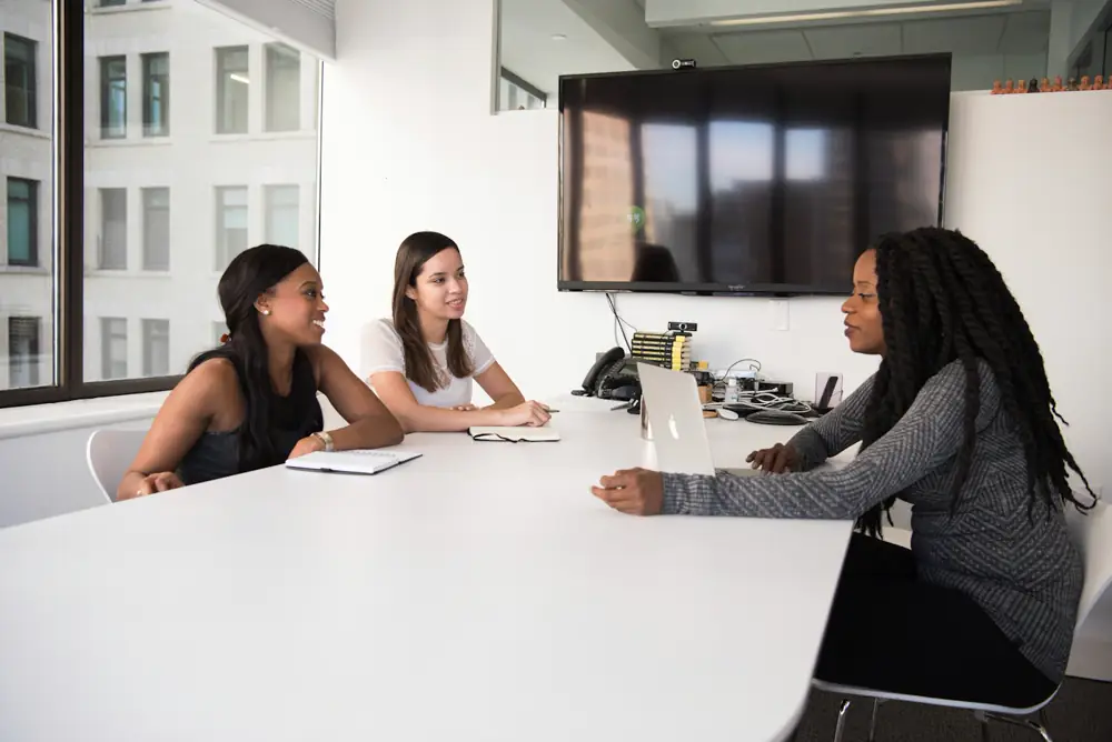 Three colleagues discussing a shortlist around a meeting table