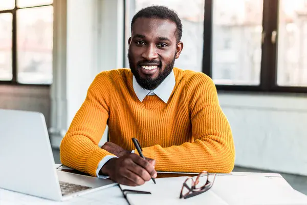 A smiling jobseeker at a desk with a laptop